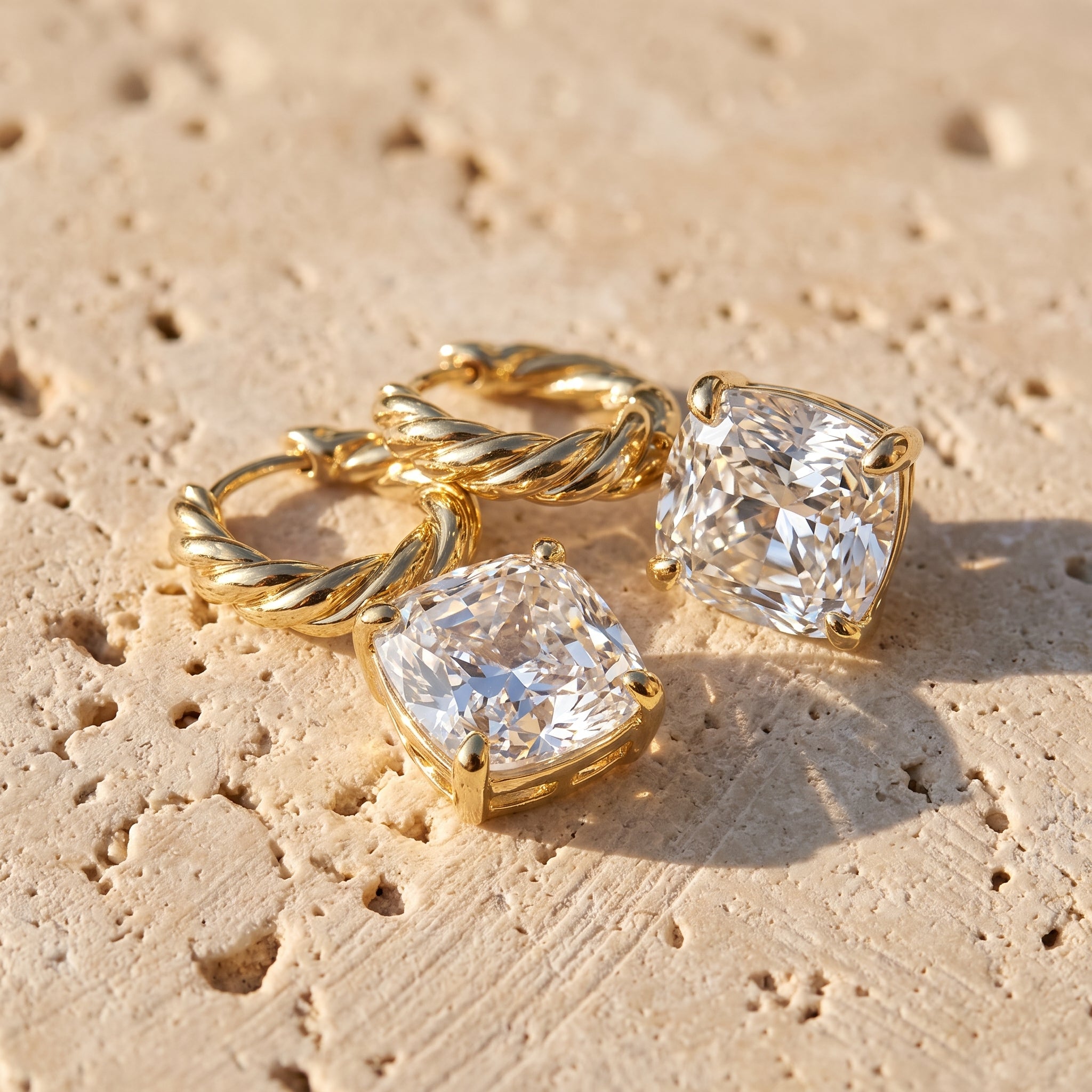 Cushion Drop Diamond Hoops in 14k yellow gold resting on Jerusalem limestone in late afternoon sun