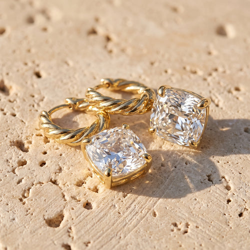 Cushion Drop Diamond Hoops in 14k yellow gold resting on Jerusalem limestone in late afternoon sun
