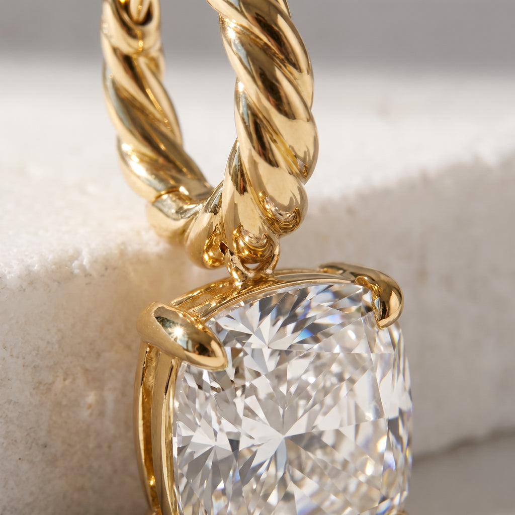 Macro detail of the twisted rope hoop and four-prong cushion diamond drop in 14k gold