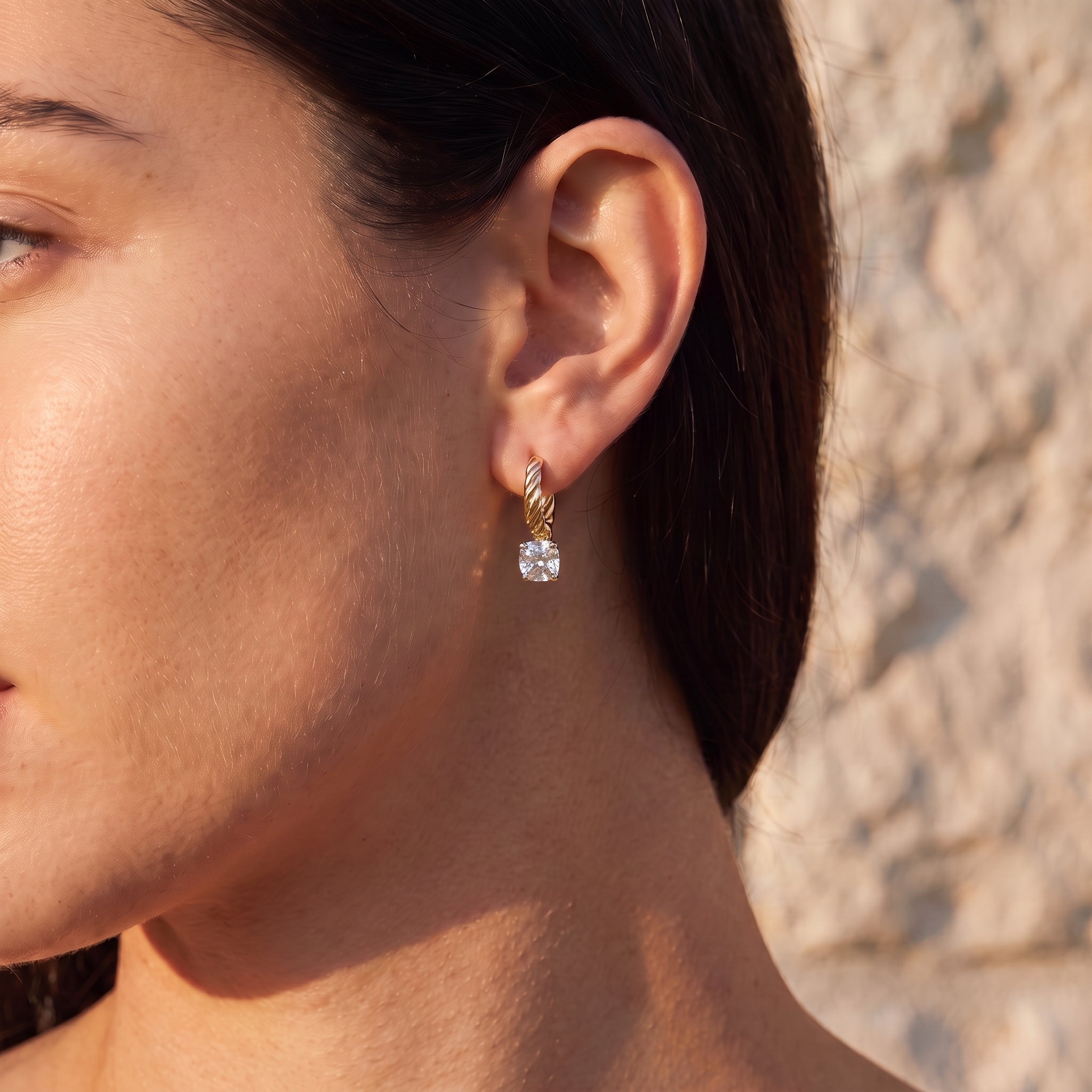 Cushion Drop Diamond Hoop worn on the ear in golden hour light against Jerusalem stone