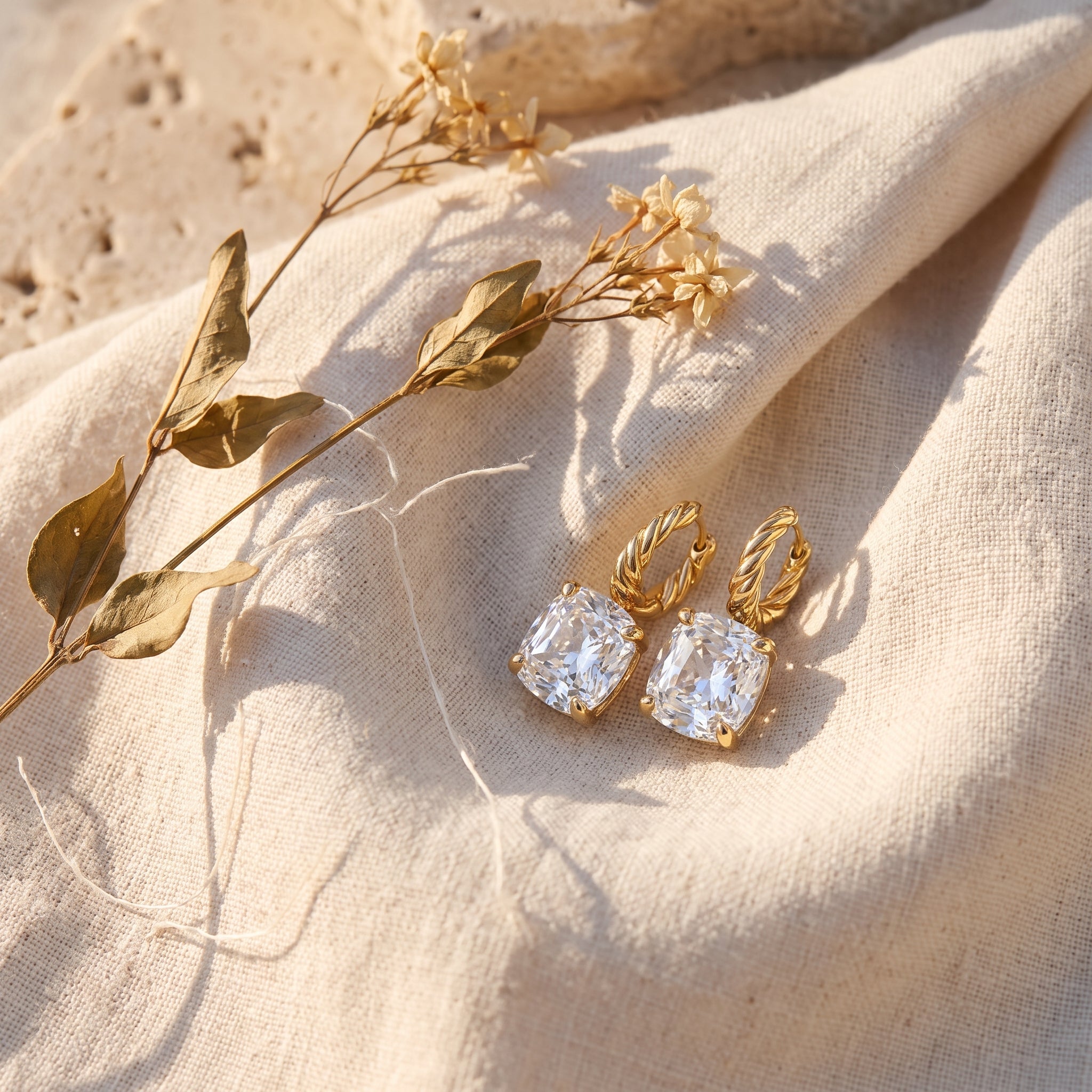 Cushion Drop Diamond Hoops among dried jasmine on raw linen
