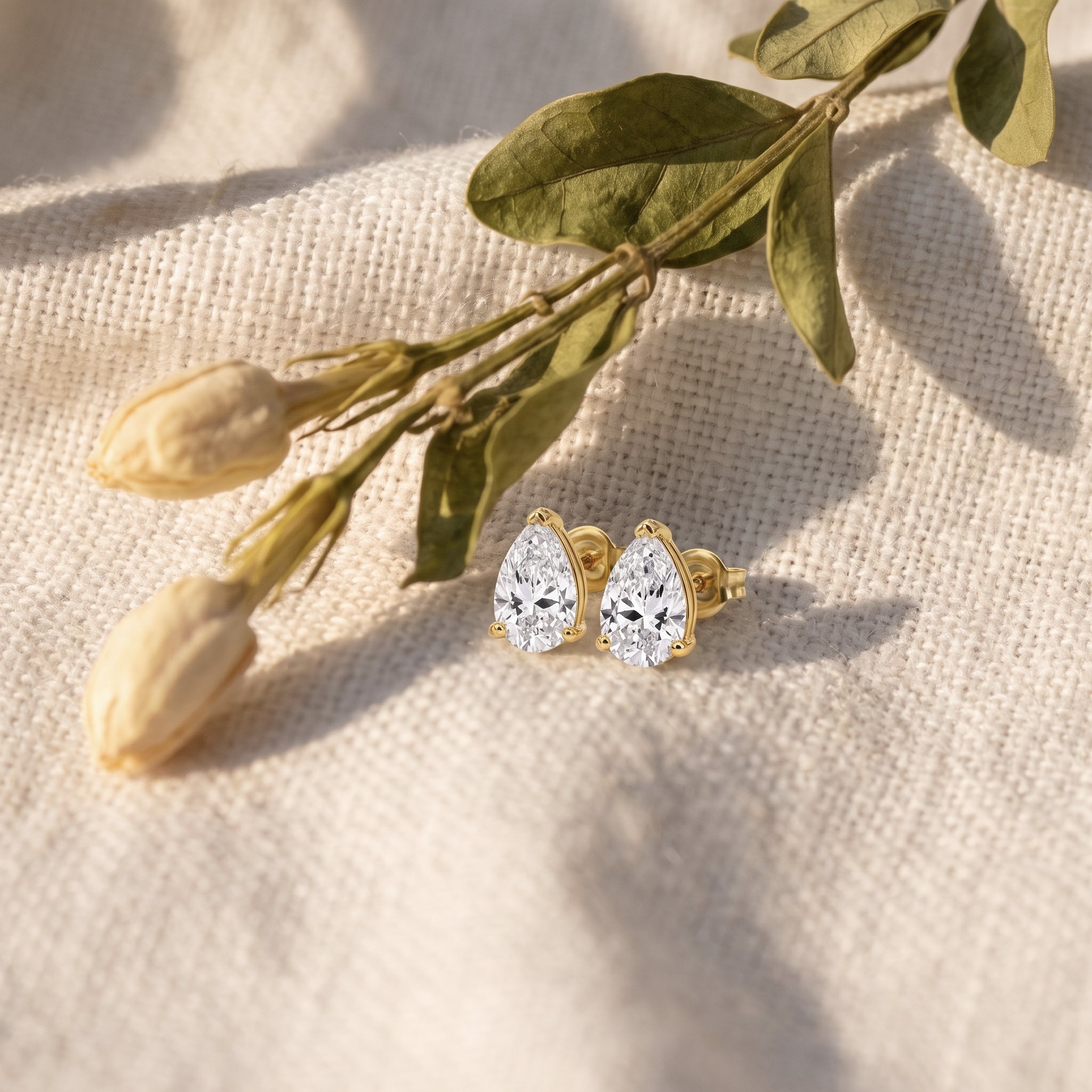 Leah's Tear pear studs on oatmeal linen with dried tulip buds and olive leaves