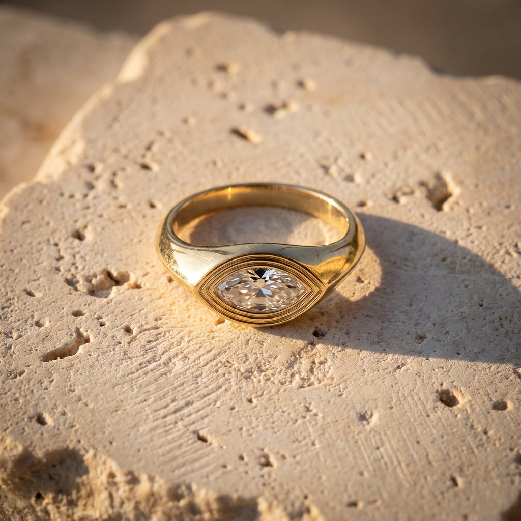 Leah's Whisper east-west marquise signet in 14k yellow gold on raw Jerusalem stone in golden-hour light