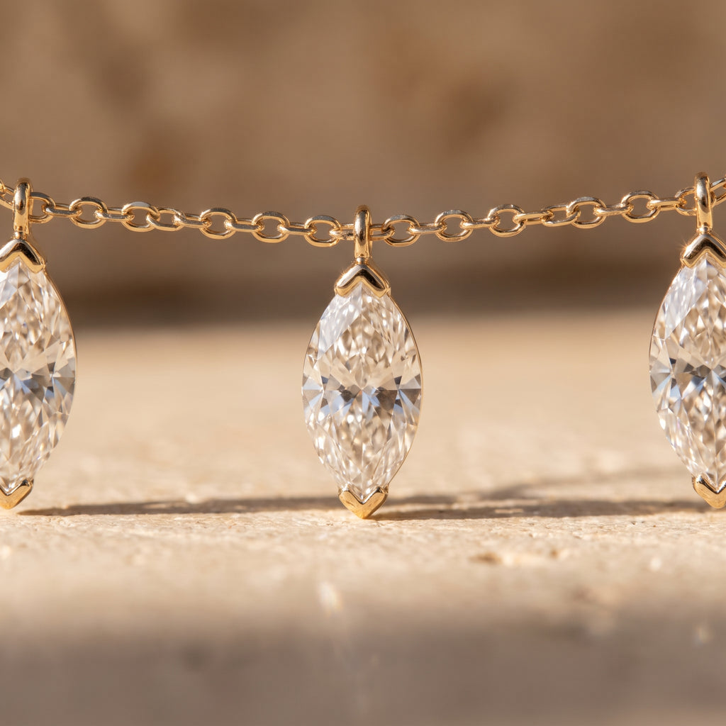 Macro detail of three marquise diamonds hanging free from the fine gold cable chain