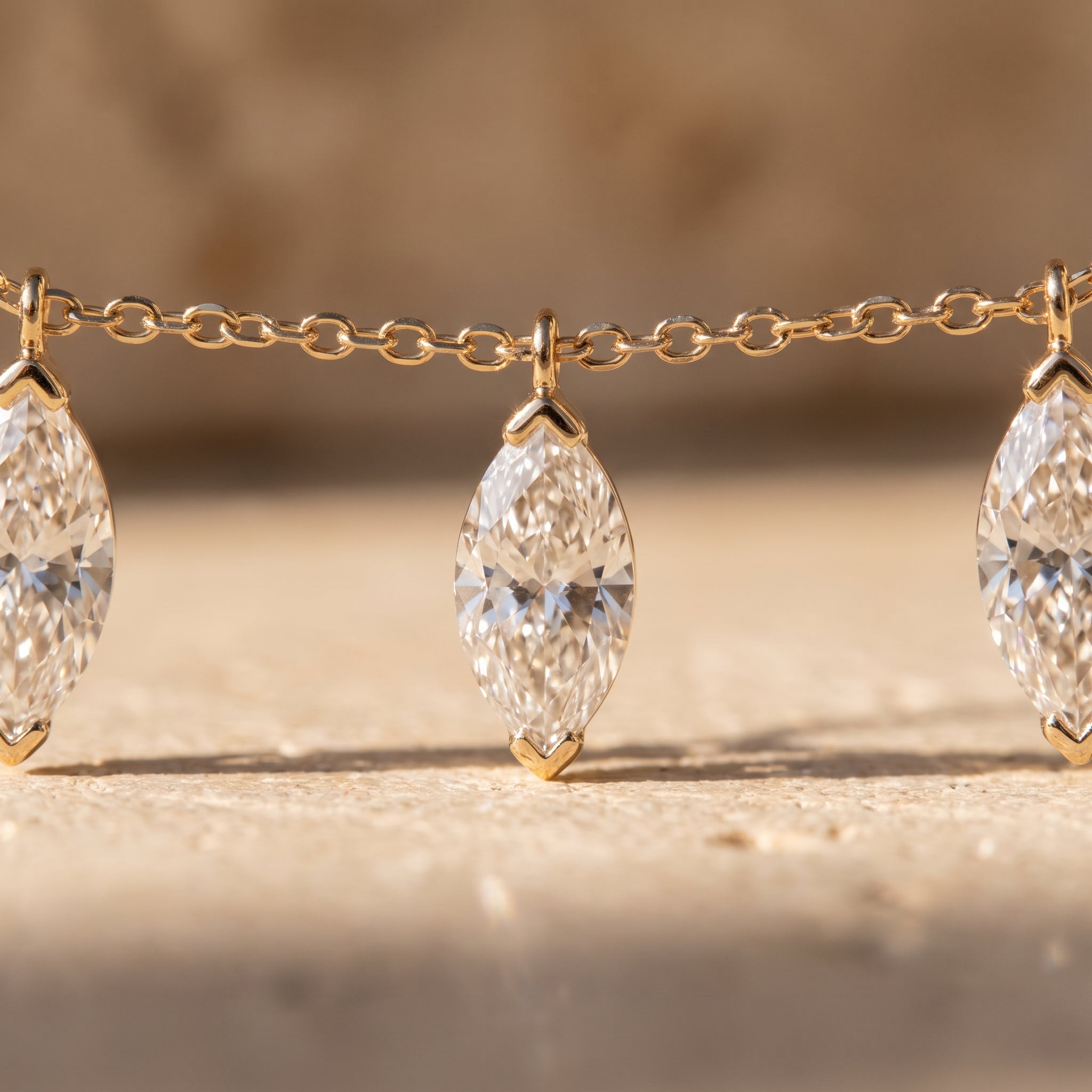 Macro detail of three marquise diamonds hanging free from the fine gold cable chain