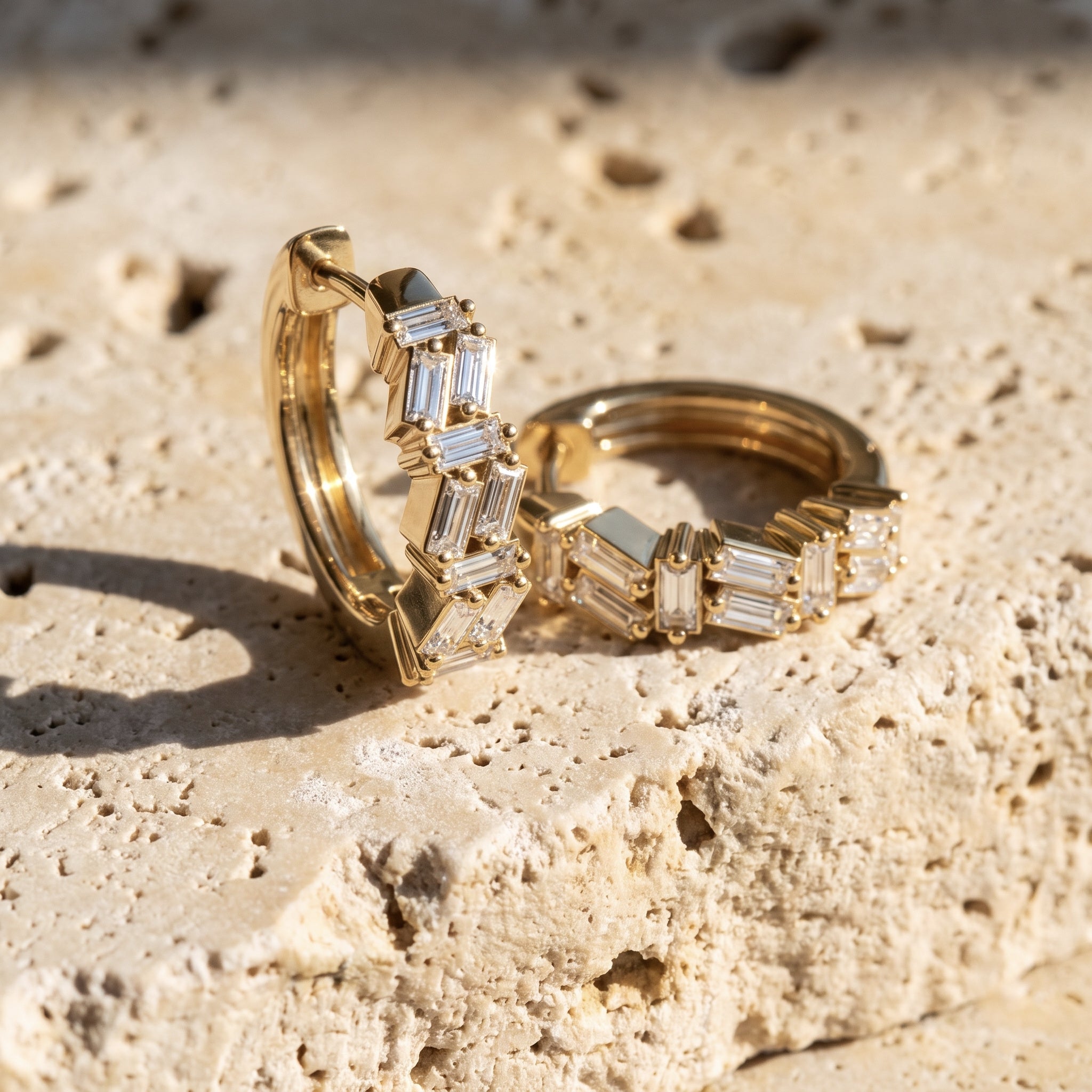 Sarah's Ember scattered-baguette huggie hoops in 14k yellow gold on raw Jerusalem stone