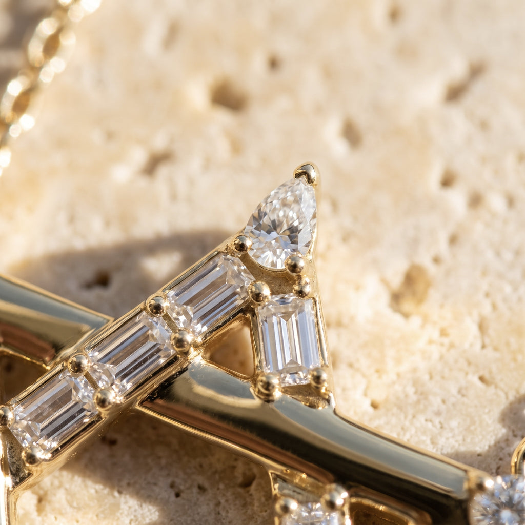 Macro detail of Sarah's Shield: pear-cut diamond tip and channel-set baguettes on the polished 14k yellow gold bar