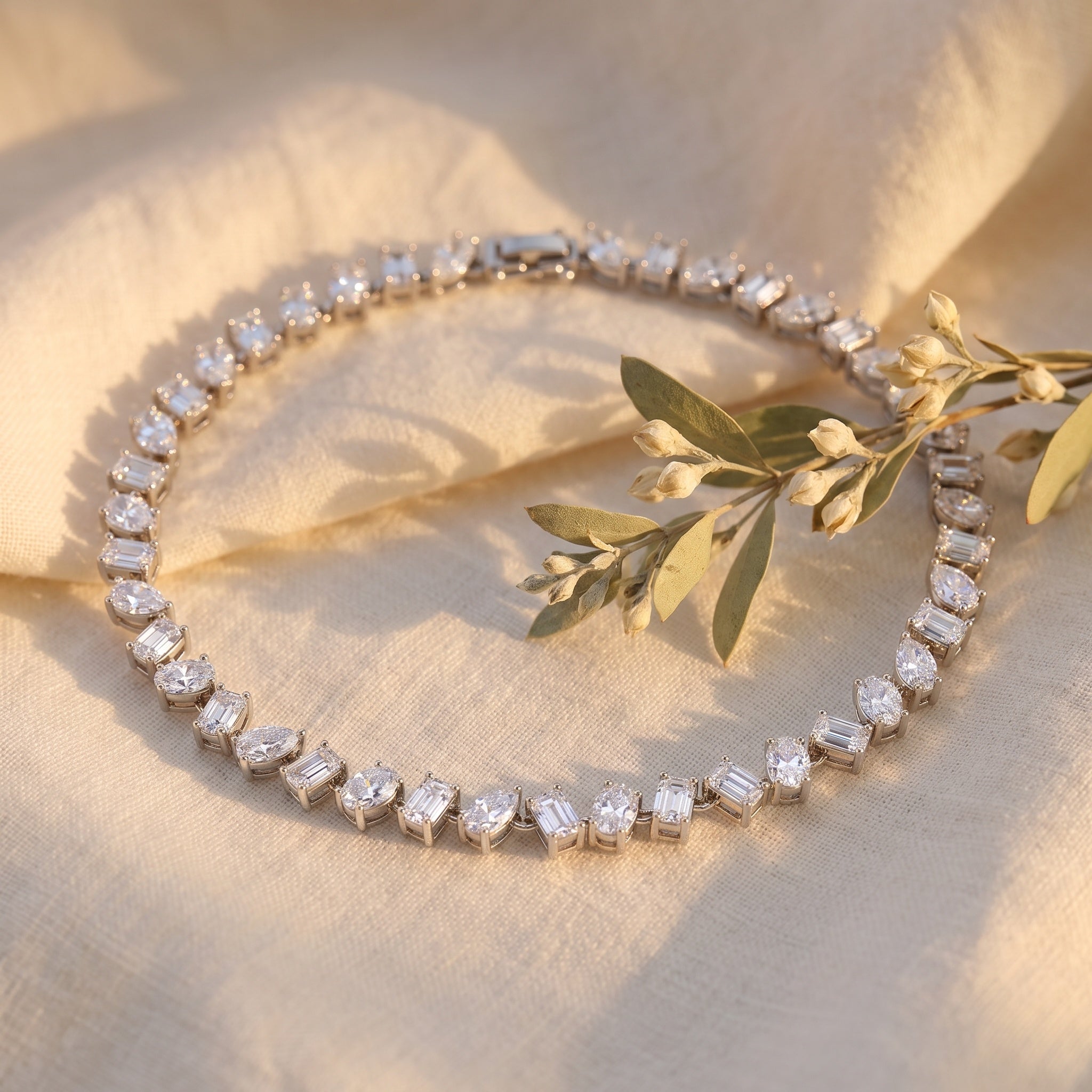 The Emora Tennis Bracelet resting on linen with dried botanicals